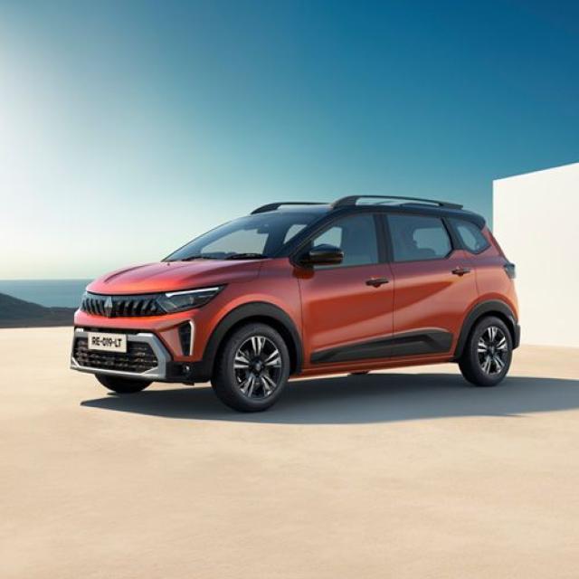 Orange compact SUV with black roof rails parked on a pale concrete surface under a clear blue sky.