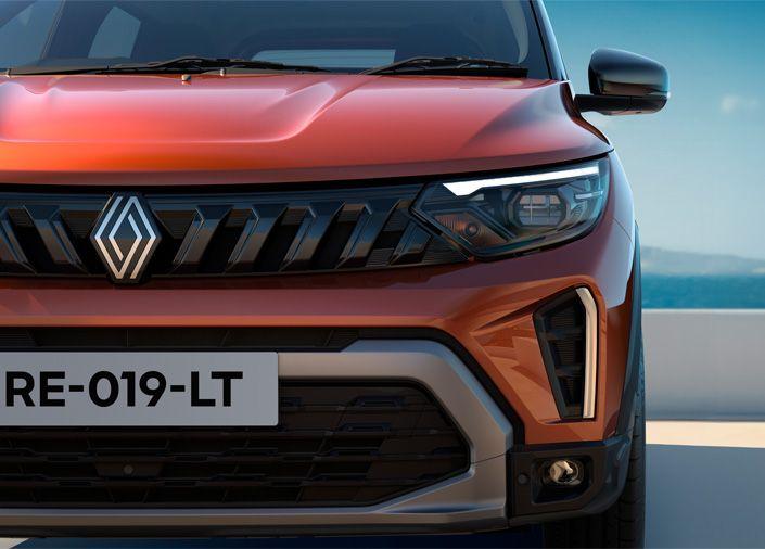 Front view of an orange Renault SUV showing the grille, emblem, and angular LED headlight with a visible license plate reading RE-019-LT on a bright day near a barrier.