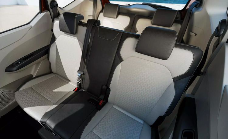 Car back seat interior with three seats, light upholstery, and visible seat belts in use.