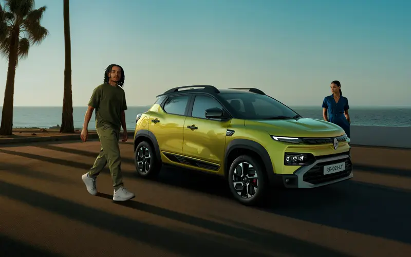 Yellow-green SUV parked on a seaside road with two people walking nearby and palm trees in the background by the ocean at sunset light.