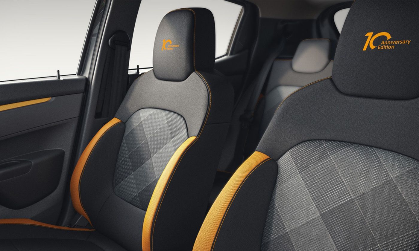 Car interior showing dark gray seats with orange piping and a 10th Anniversary Edition logo on the headrest.