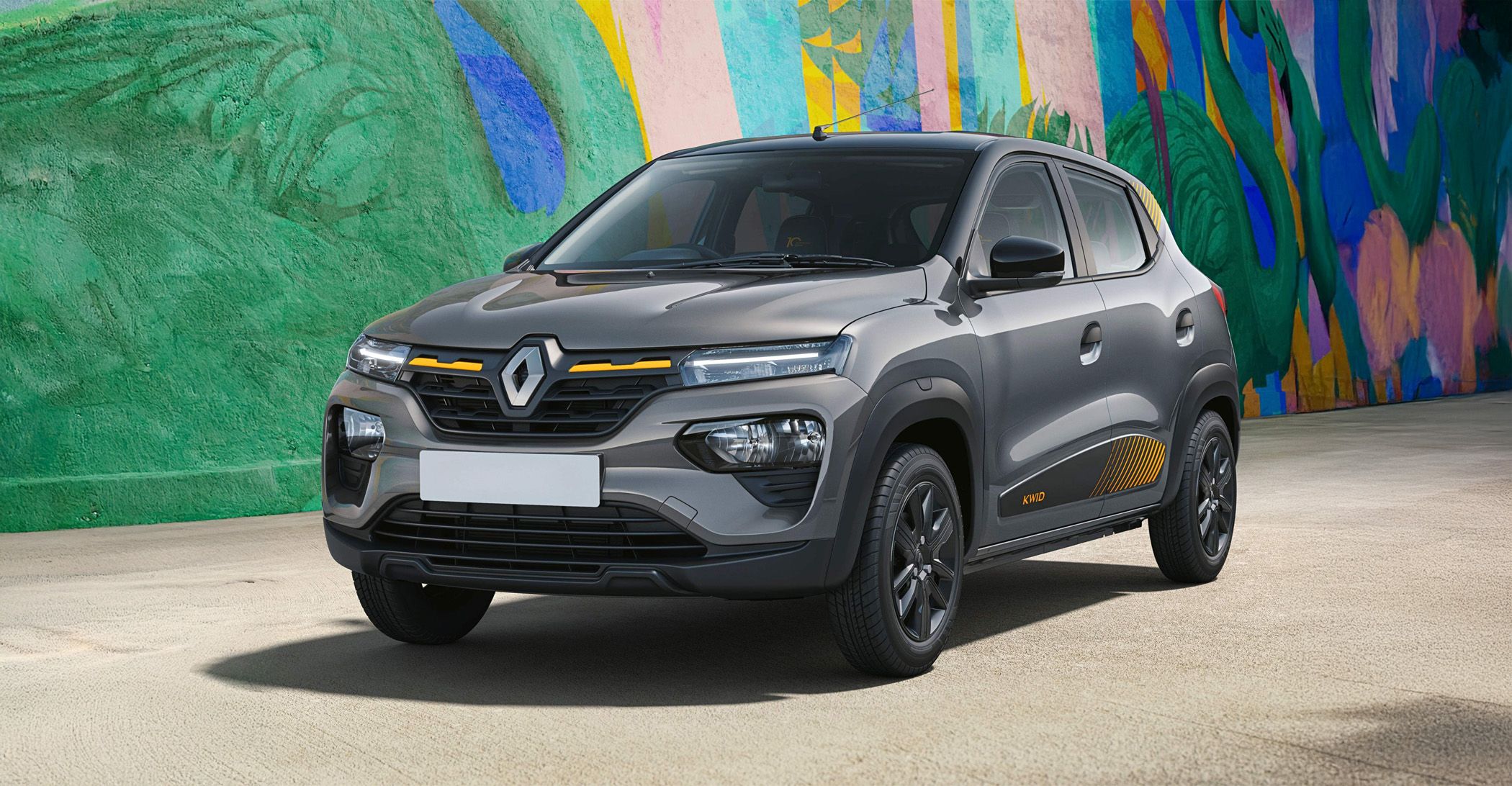 Grey Renault compact SUV parked in front of a bright, colorful mural-styled wall, rear shadow on the ground.