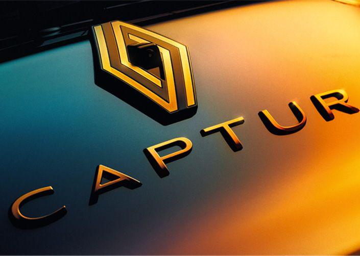 Close-up of the Captur badge on a car, with a gold geometric emblem and the word CAPTUR in a warm gradient finish.